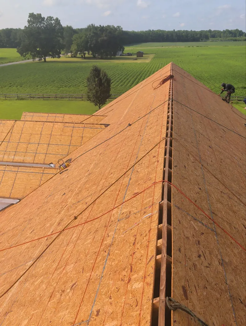 New roof decking panels installed along a ridge, with a ventilation slot at the peak