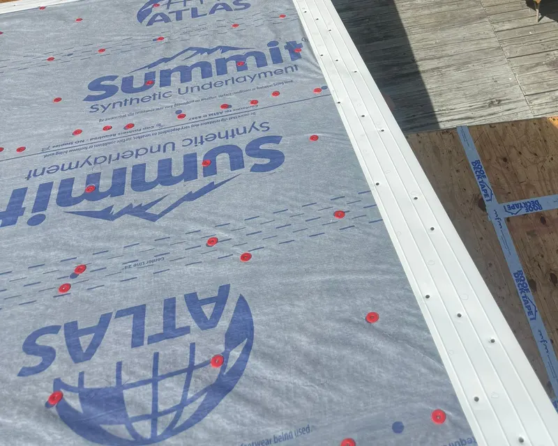 White metal drip edge along a roof edge over synthetic underlayment