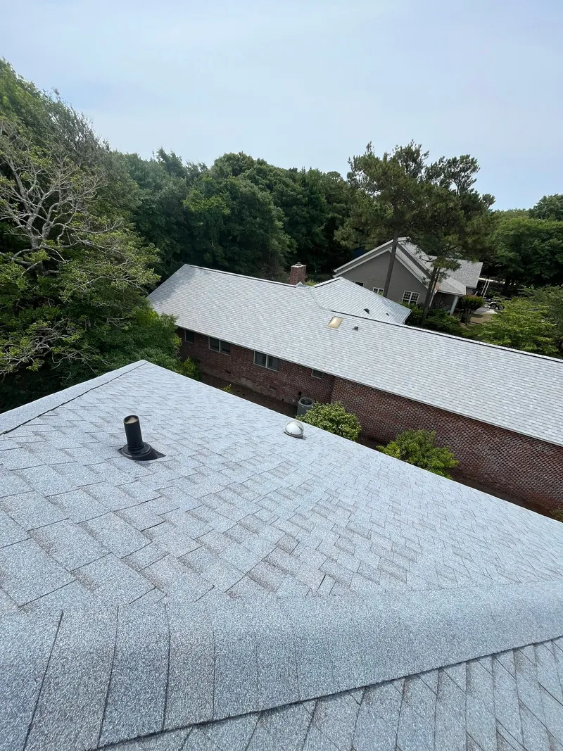 Vent pipe boot and a skylight on a new gray shingle roof