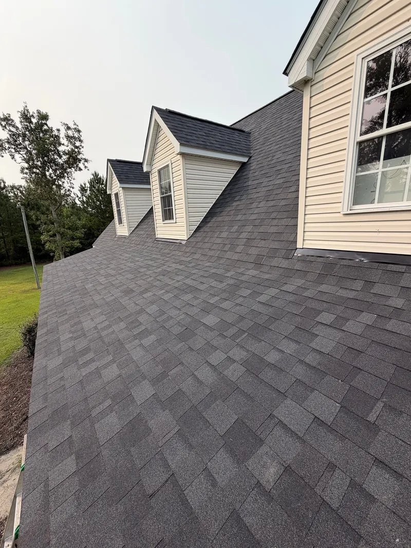 Finished charcoal shingle roof seen along the slope past two dormers