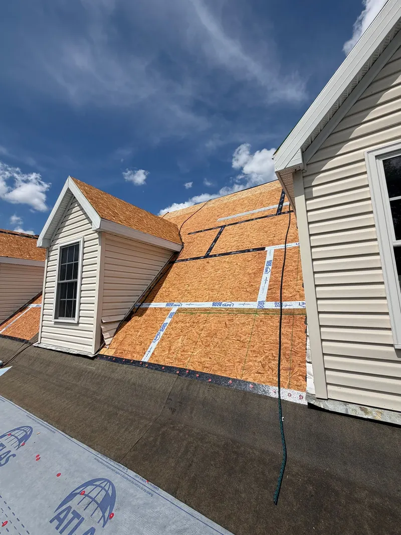 Taped deck seams around a dormer, with synthetic underlayment at the eave