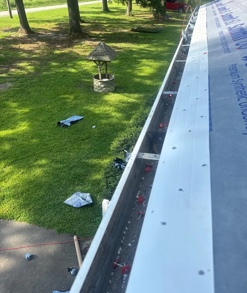 Long run of white drip edge along an eave with underlayment beside it