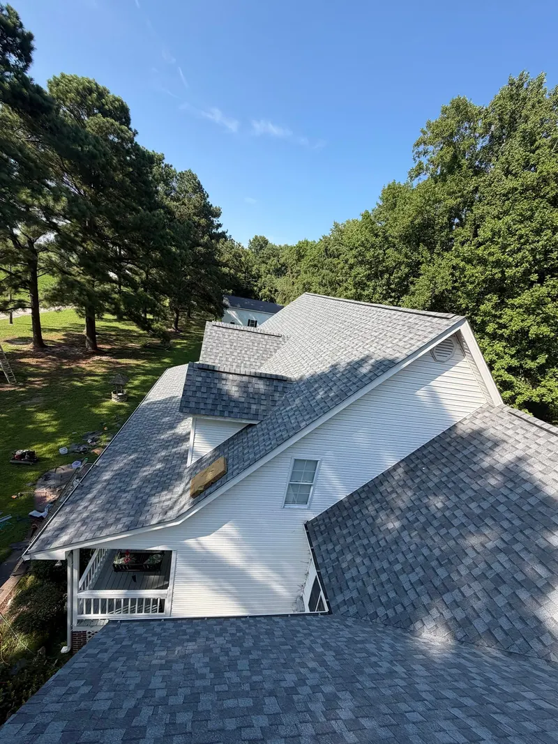 Aerial view of a finished gray shingle roof with dormers on a white house