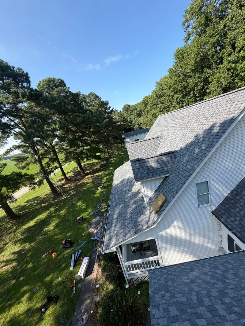 Aerial view of a finished gray shingle roof and white gable on a sunny day