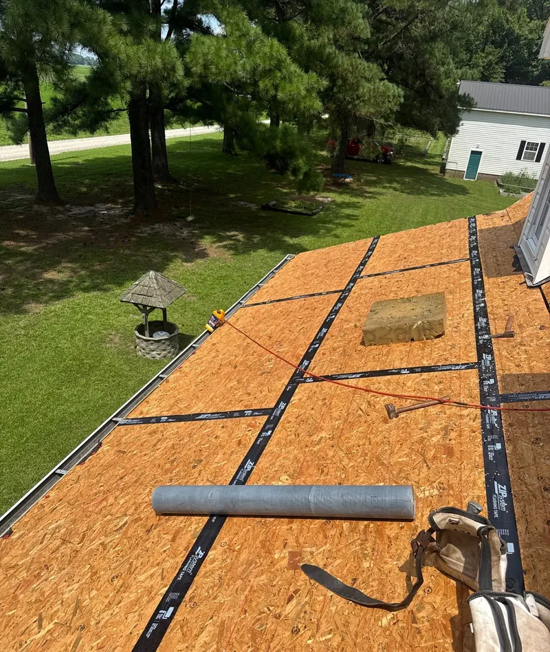 Taped seams across an OSB roof deck with a roll of underlayment ready beside them