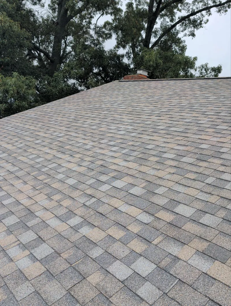 New architectural shingles on a roof slope near a chimney