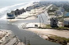 Aerial view of oceanfront homes and a washed-out road after a hurricane breached the island